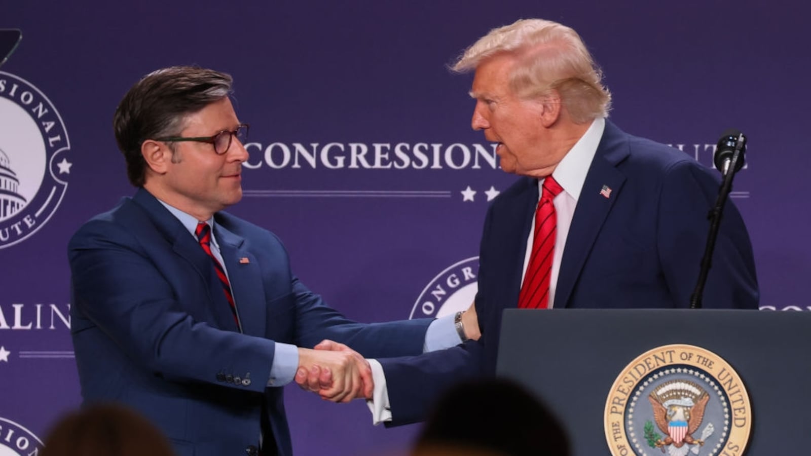 President Donald Trump shakes hands with House Speaker Mike Johnson