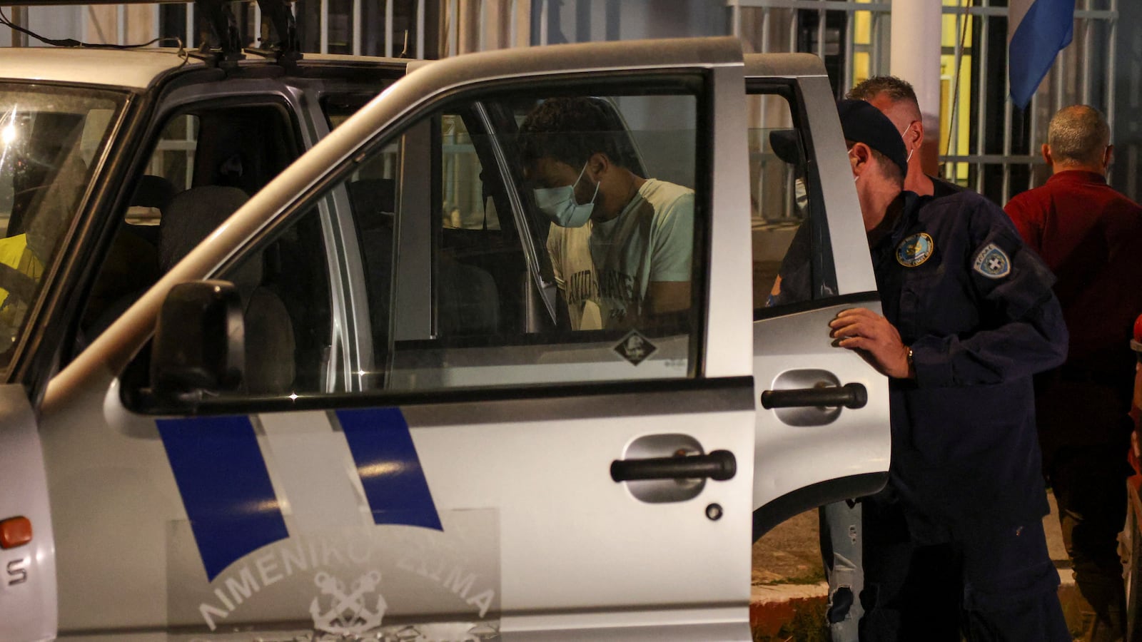 Port police officer escort an Egyptian man, part of a group of nine Egyptian, who were arrested under the accusations of causing the shipwreck of a boat with migrants that capsized at open sea off Greece, in Kalamata, Greece, June 15, 2023.