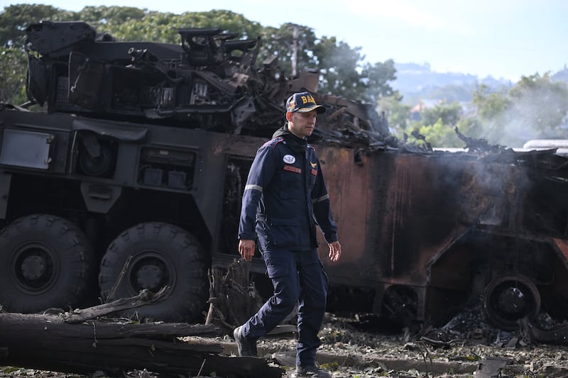 A man in front of a burned out fighting vehicle