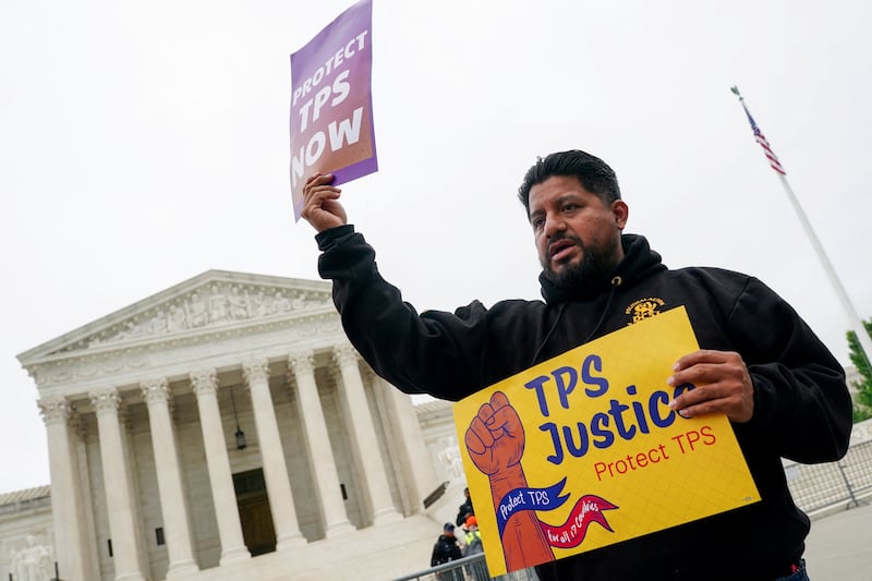 A man holds placards as immigrants' rights activists and demonstrators attend a rally outside the U.S. Supreme Court, as justices were scheduled to hear arguments on whether the administration of U.S. President Donald Trump can end the Temporary Protected Status (TPS) of Syrian and Haitian nationals, in Washington, D.C., U.S., April 29, 2026.