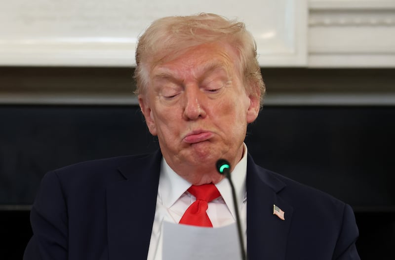 President Donald Trump reads a note during a roundtable discussion in the State Dining Room of the White House on October 08, 2025 in Washington, DC.
