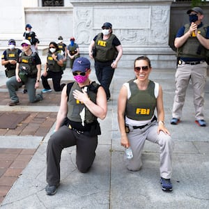Federal Bureau of Investigation (FBI) officers take a knee with demonstrators, as they march on Pennsylvania Av. Thursday, June 4, 2020, in Washington, during a protest over the death of George Floyd, an unarmed black man, who died after a police officer kneeled on his neck for several minutes.