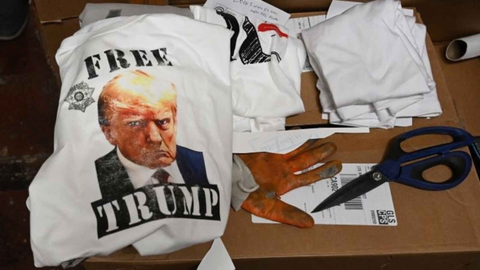 A shirt reading "Free Trump" with a picture of Donald Trump sits on a cardboard box.
