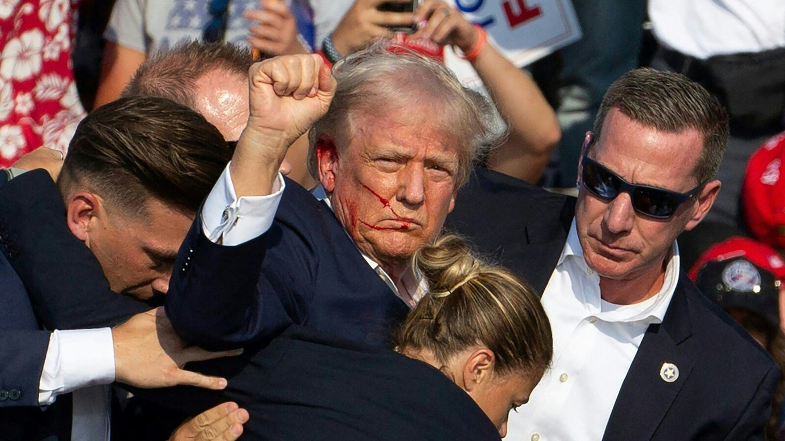 Republican candidate Donald Trump is seen with blood on his face surrounded by secret service agents on July 13, 2024.