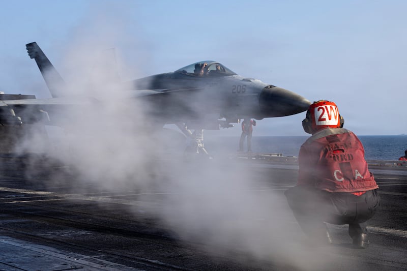 A U.S. Navy sailor prepares to launch an F/A-18E Super Hornet from the flight deck of the USS Abraham Lincoln.
