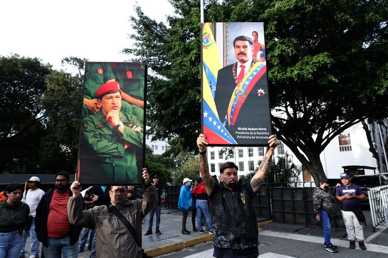 CARACAS, VENEZUELA - JANUARY 03: Supporters of Nicolas Maduro and late Hugo Chavez hold posters with their images after explosions and low-flying aircraft were heard on January 03, 2026 in Caracas, Venezuela. According to some reports, explosions were heard in Caracas and other cities near airports and military bases around 2 am. US President Donald Trump later announced that his country's military had launched a "large-scale" attack on Venezuela and captured its President Nicolas Maduro and his wife. (Photo by Jesus Vargas/Getty Images)