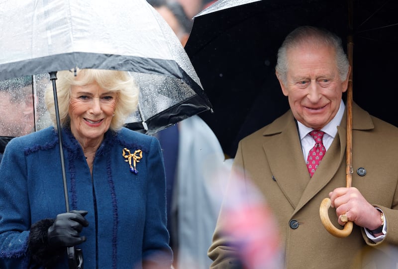 Queen Camilla and King Charles III shelter under umbrellas as they meet members of the public during a walkabout after visiting The Sun Inn on February 5, 2026, in Dedham, Essex.