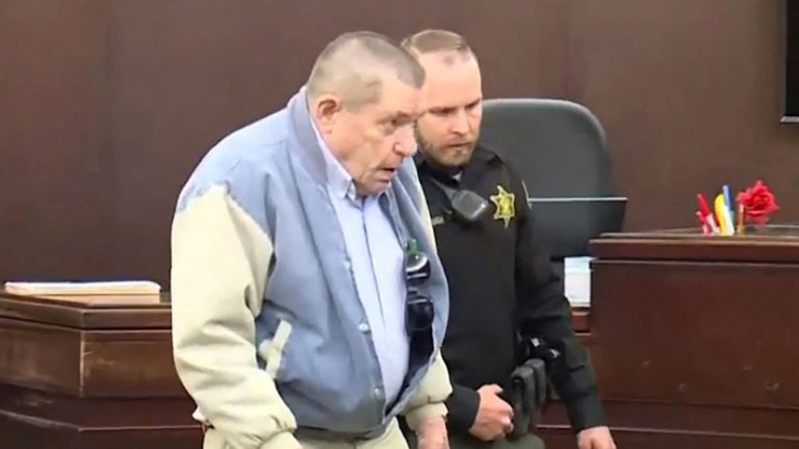 Andrew Lester is escorted by a police officer in court.
