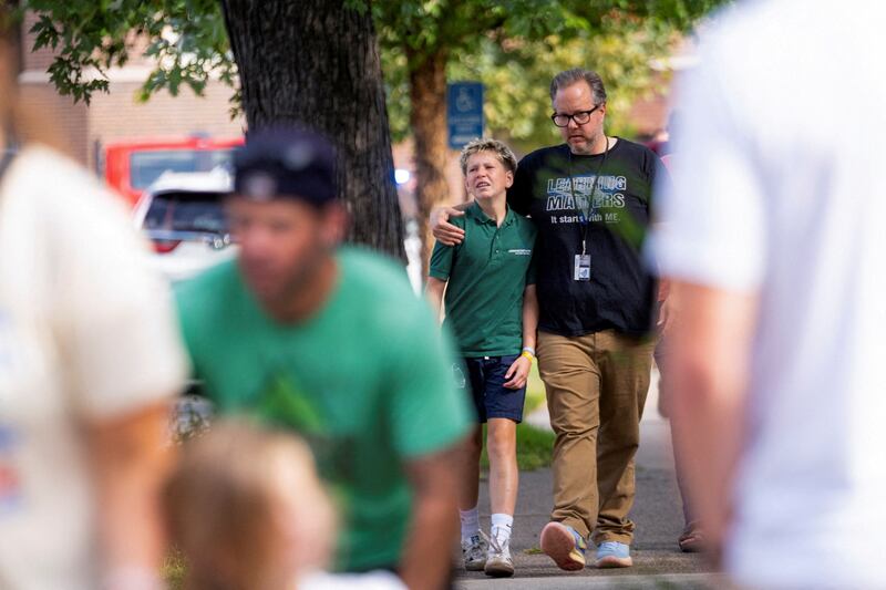 Families and loved ones walk outside the police barricades after a shooting at Annunciation Church, which is also home to an elementary school, in Minneapolis, Minnesota, on Aug. 27, 2025.
