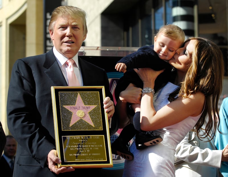 Donald Trump holds a replica of his star on the Hollywood Walk of Fame as his wife Melania holds their son Barron