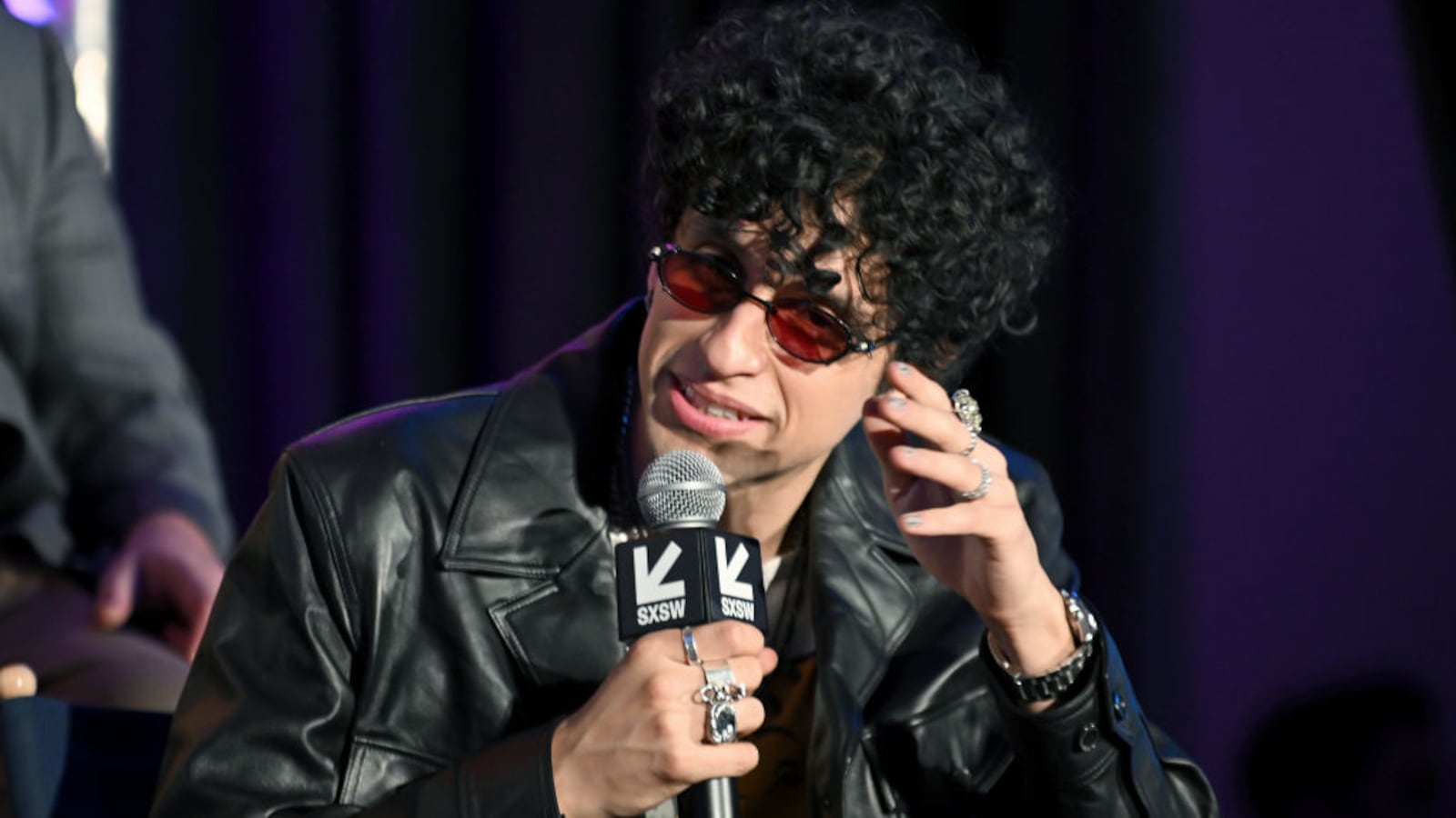 Sebastian Chacon holds a microphone while speaking on stage at an event.
