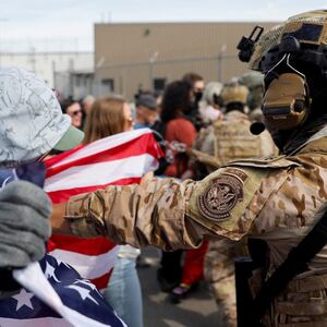 A demonstrator holding an American flag is pushed back by a U.S. Immigration and Customs Enforcement officer during a protest outside an ICE facility, weeks after U.S. President Donald Trump ordered increased federal law enforcement presence and stepped-up immigration enforcement actions by the Department of Homeland Security, in Broadview, Illinois, U.S., September 12, 2025.