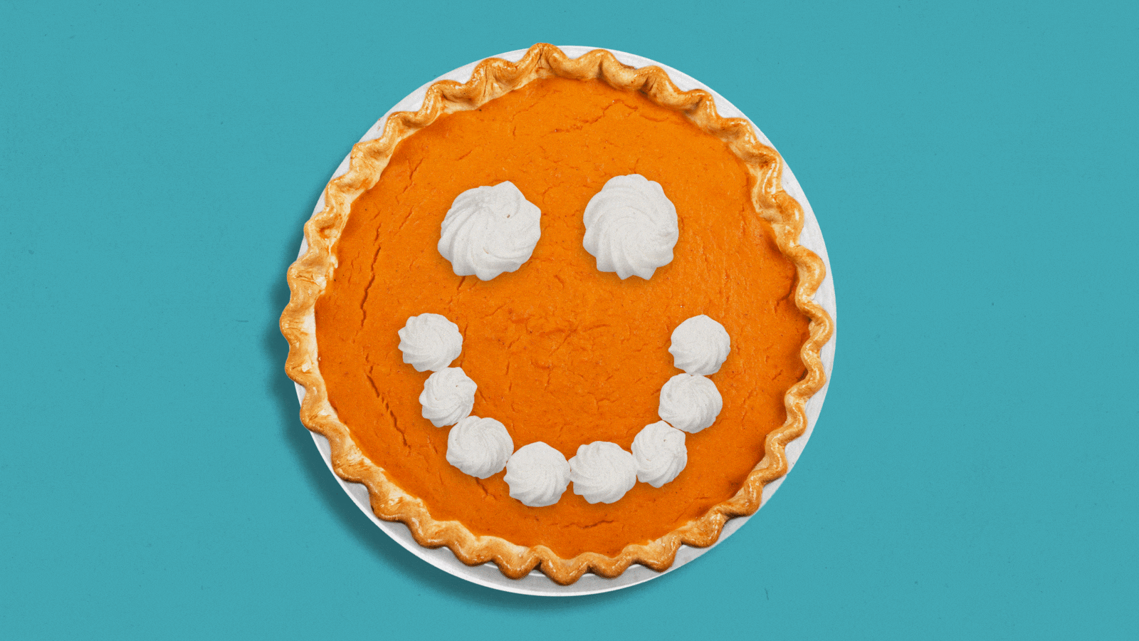 thanksgiving pumpkin pie with a smiley face of whipped cream winking