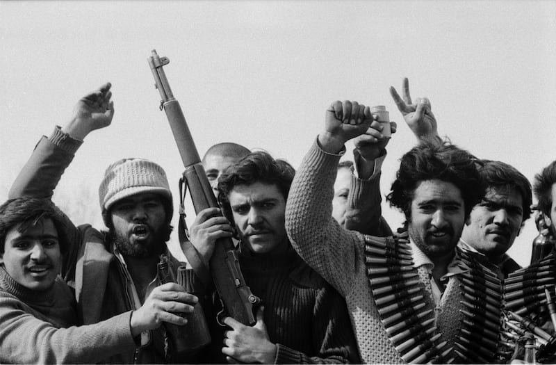 A group of men carrying arms and ammunitions raise their hands victoriously while driving around the city after having looted army garrisons in the late afternoon on the victory day of the Iranian Revolution in Tehran, Iran, 11th February 1979. (Photo by Kaveh Kazemi/Getty Images)