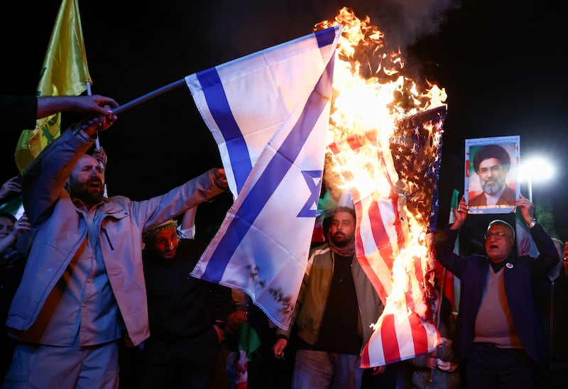A man holds a photo of Iran's Supreme Leader, Mojtaba Khamenei, while the flags of the U.S. and Israel are burnt, as people gather after a two-week ceasefire in the Iran war was announced, in Tehran, Iran, April 8, 2026.