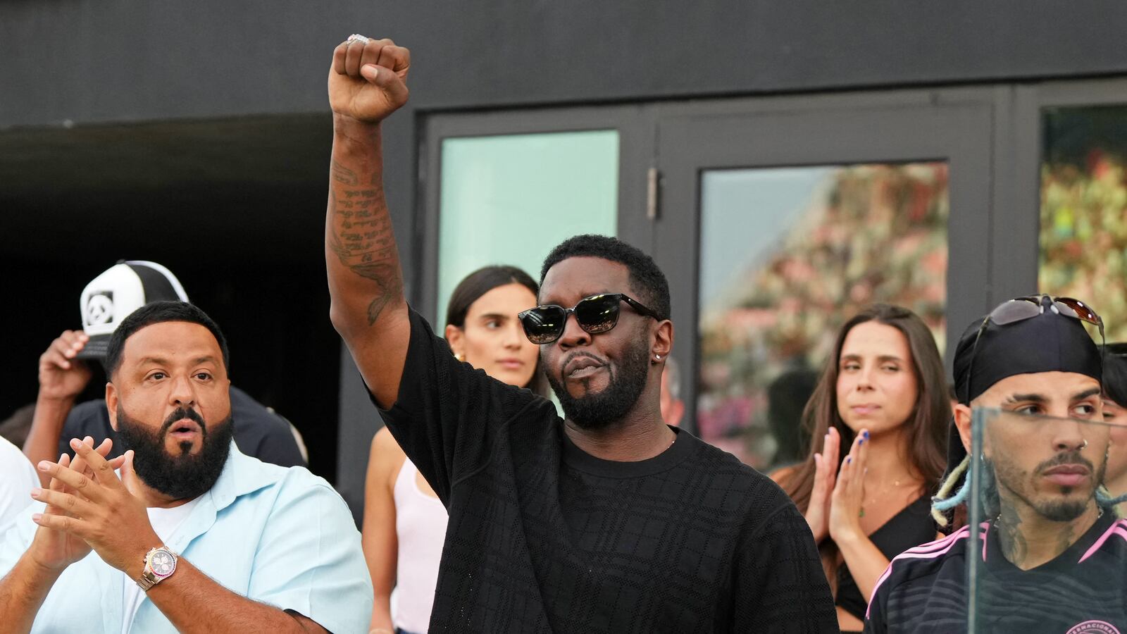 Diddy raising his fist with DJ Khaled behind him