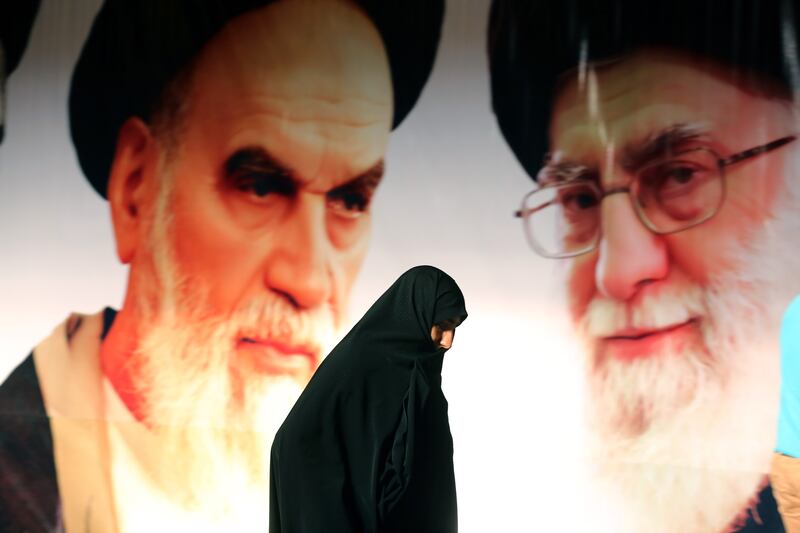 An Iranian woman walks past a giant poster showing supreme leader, Ayatollah Ali Khamenei (R) and the founder of Iran's Islamic Republic, Ayatollah Ruhollah Khomeini (L) during a ceremony marking the 36th anniversary of his return from exile on February 1, 2015 at Khomeini's mausoleum in a suburb of Tehran.