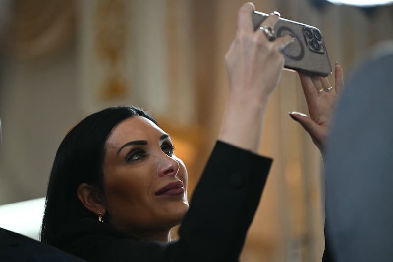 Political activist Laura Loomer films with her cellphone as US President Donald Trump takes part in a dedication ceremony for Southern Boulevard, in the ballroom at Mar-a-Lago in Palm Beach, Florida, on January 16, 2026.