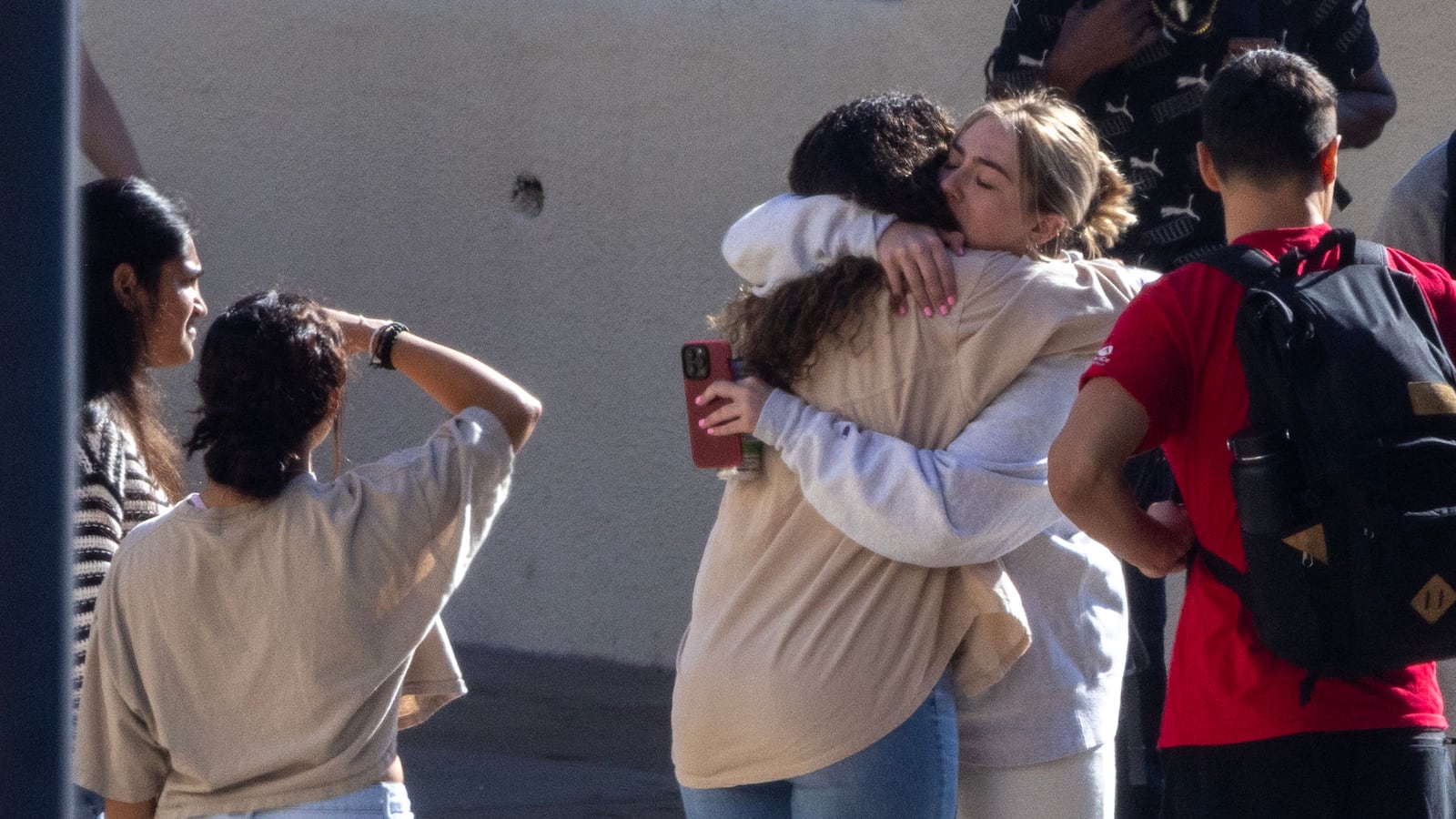 Pepperdine University students embrace as students, faculty and greater campus community members make a somber procession into the Firestone Field house for a vigil honoring four students