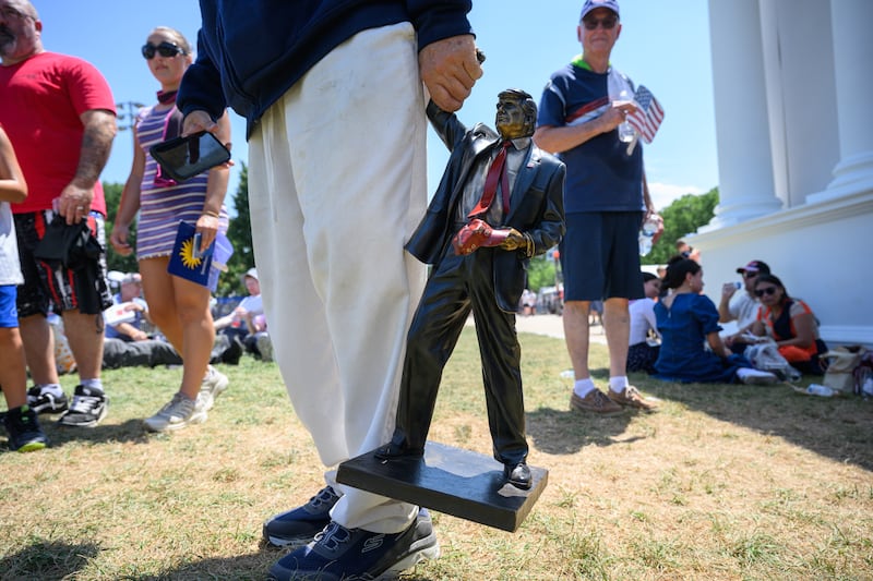 A person carries a miniature statue of U.S. President Donald Trump at The Great American State Fair along the National Mall on July 04, 2026 in Washington, DC.