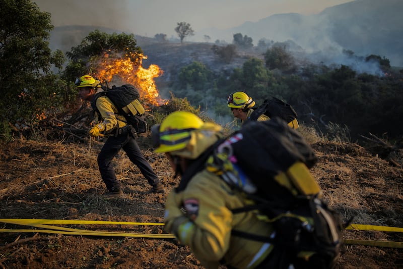 Firefighters climb up a hillside to clear brush during a wildfire known as the Sandy Fire, in Simi Valley, California, U.S., May 18, 2026.