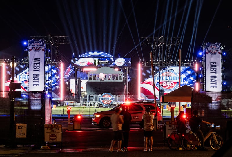 People stop to look and take pictures as stage lights are tested for the upcoming Ultimate Fighting Championship Freedom 250 event on the South Lawn of the White House.