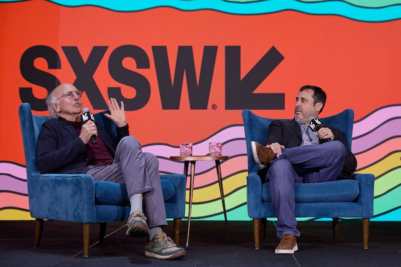 Larry David and Jeff Schaffer talking on stage at a South by SouthWest event.