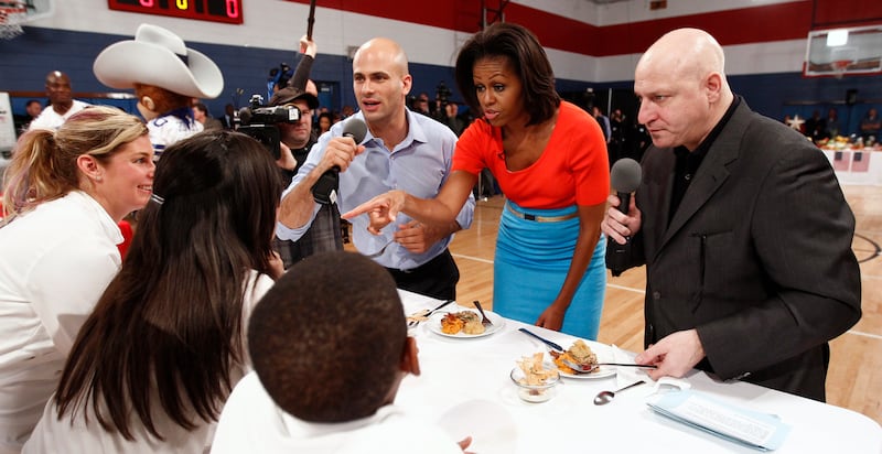 U.S. first lady Michelle Obama (C) judges food, along with assistant White House chef and food initiative coordinator Sam Kass (L) and "Top Chef" judge Tom Colicchio, during a taping of the TV cooking show "Top Chef" in Dallas, Texas February 10, 2012. During the contest on the show, children paired up with top chefs to prepare low-cost, healthy school lunches. The first lady is on a three-day trip to mark the two-year anniversary of her "Let's Move" initiative.