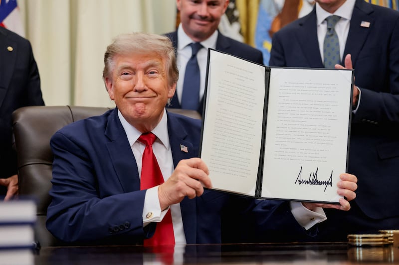 U.S. President Donald Trump holds up an executive order related to Utah protected lands after signing it in the Oval Office at the White House in Washington, D.C., U.S., July 13, 2026.