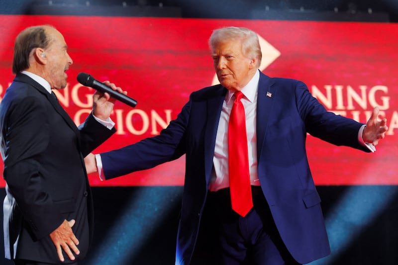 U.S. President Donald Trump gestures onstage as Lee Greenwood sings during a memorial service for slain conservative commentator Charlie Kirk at State Farm Stadium, in Glendale, Arizona, U.S., September 21, 2025.