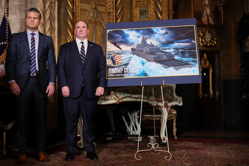 U.S. Secretary of Defense Pete Hegseth and Secretary of the Navy John Phelan stand by a rendering of the 'Trump Class' USS Defiant, as they listen to President Donald Trump (not pictured) make an announcement about the Navy's "Golden Fleet", at Mar-a-lago in Palm Beach, Florida, U.S., December 22, 2025. REUTERS/Jessica Koscielniak