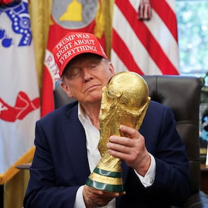 U.S. President Donald Trump holds the FIFA World Cup Trophy, as he makes an announcement on the 2026 FIFA World Cup, as FIFA president Gianni Infantino stands next to him, in the Oval Office at the White House in Washington, D.C., U.S., August 22, 2025.