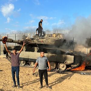 Palestinians cheer as an Israeli military vehicle burns after it was hit by Palestinian gunmen