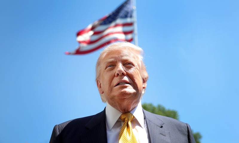 President Donald Trump speaks in front of the American flag to the press as he departs the White House on May 12, 2026 in Washington, DC.