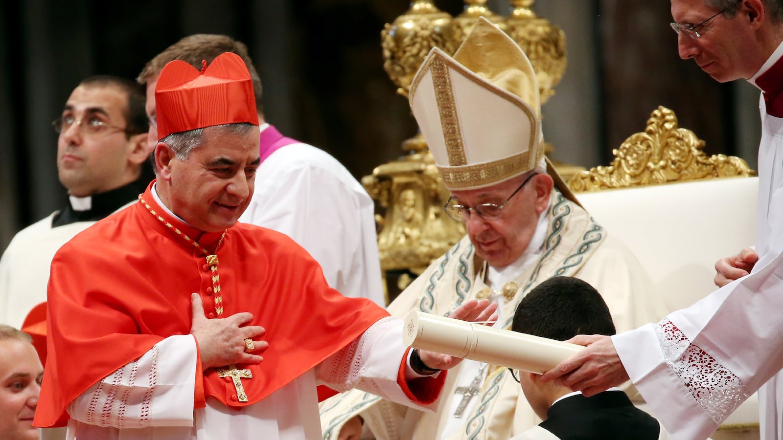 Pope Francis, dressed in white, appoints Giovanni Angelo Becciu, who is wearing red, a cardinal at the Vatican in 2018.