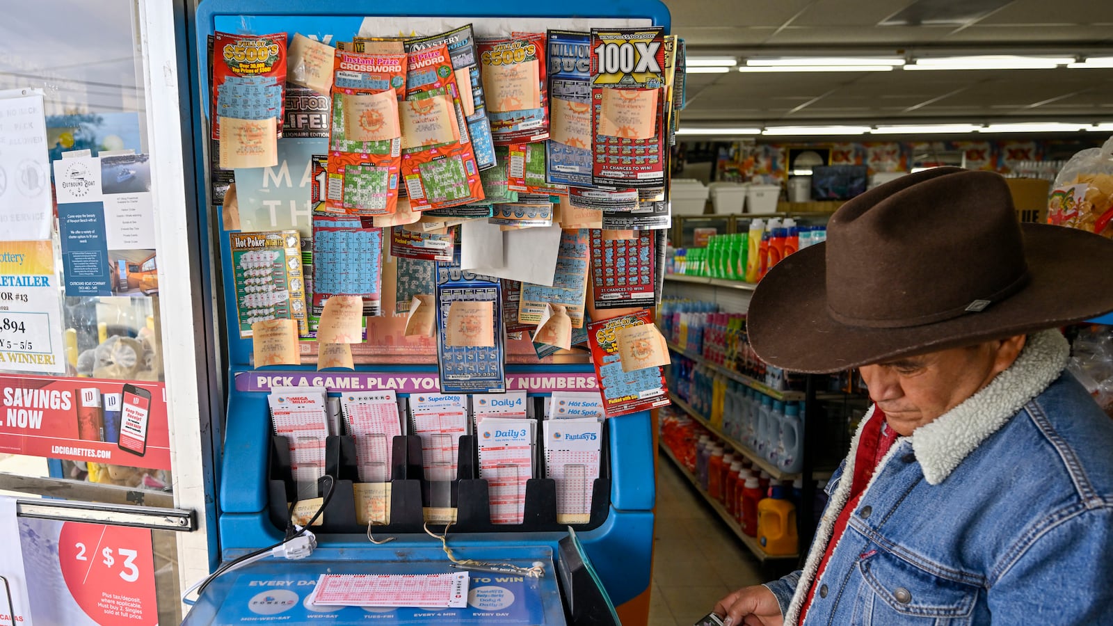 Alberto Lara checks for winning scratchers at the lottery station inside ABC Liquor in Garden Grove, CA, on Wednesday, November 2, 2022
