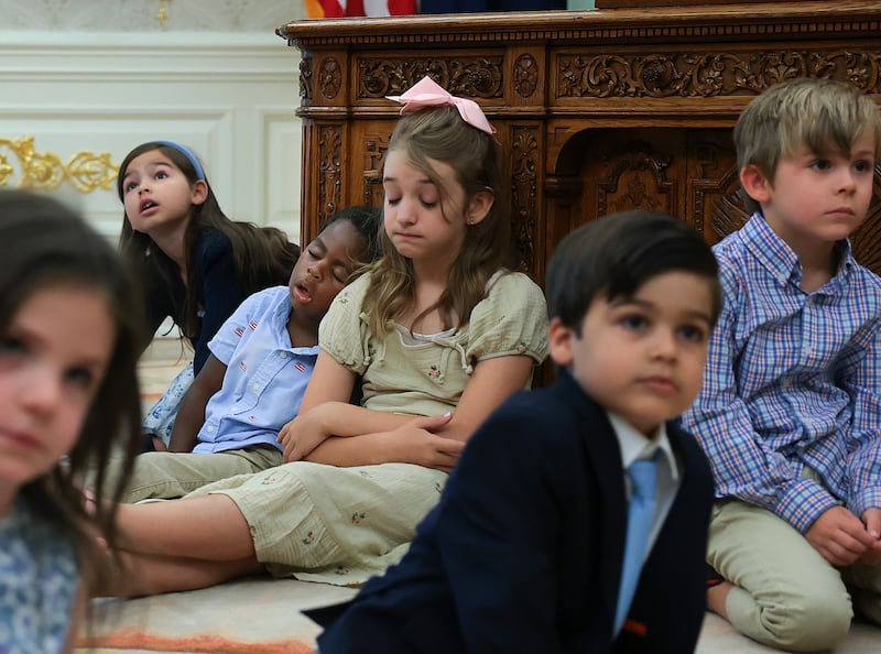 Children sit on the floor of the Oval Office and sleep against the Resolute Desk