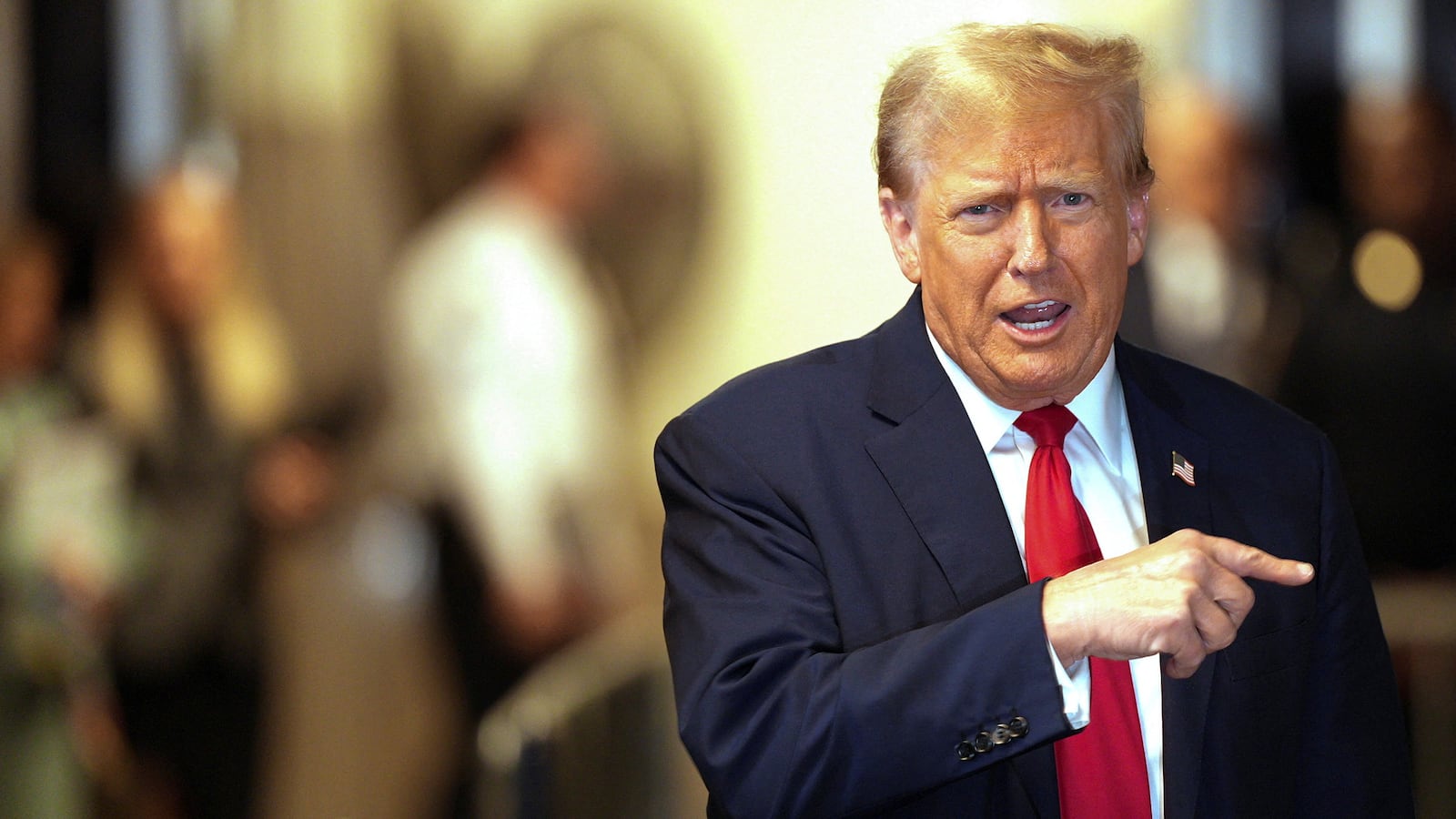 Donald Trump points to the right as he walks out of court.