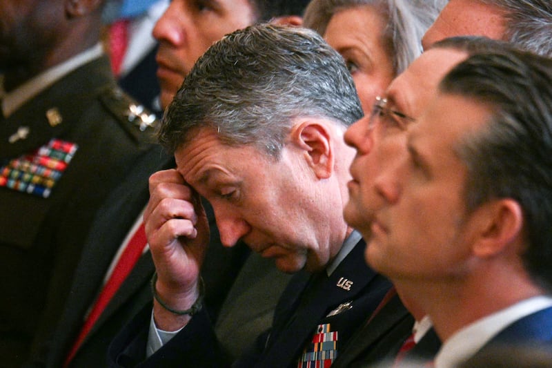 Chairman of the Joint Chiefs of Staff General Dan Caine (L) listens as US President Donald Trump speaks
