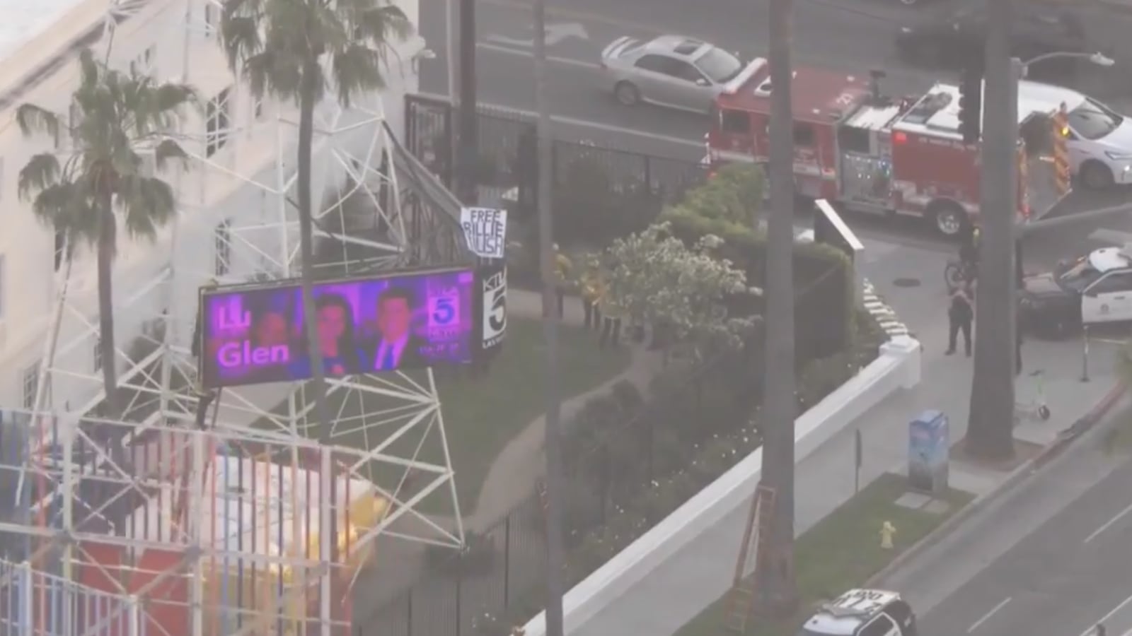 A man holds a sign reading ‘Free Billie Eilish’ on the KTLA radio tower.