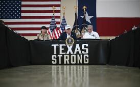 President Donald Trump and First Lady Melania Trump sit with Texas governor Greg Abbott (R) as they attend a roundtable meeting with local officials and first responders in Kerrville, Texas, on July 11, 2025.