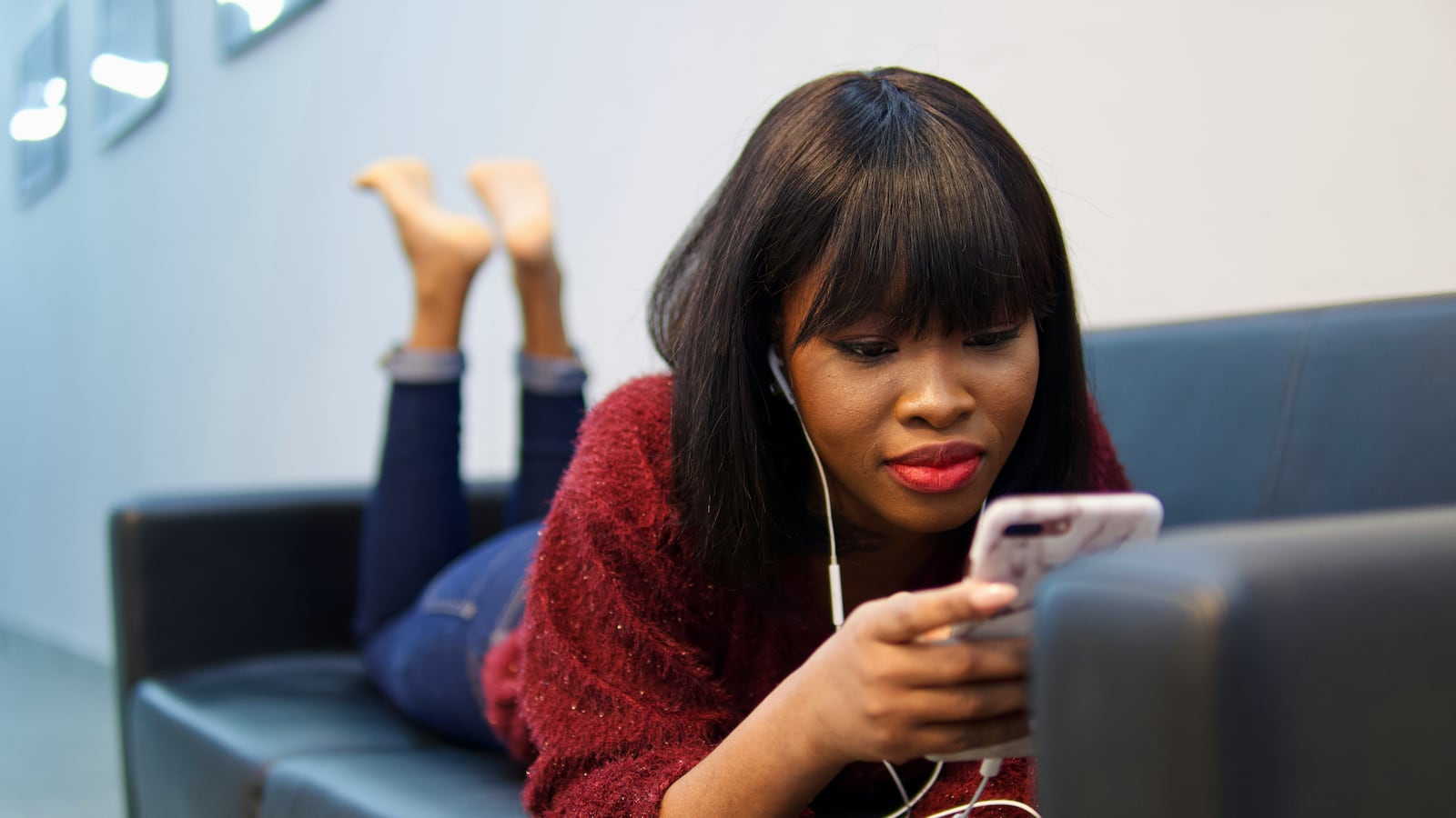 Woman wearing earphones and looking at her phone.
