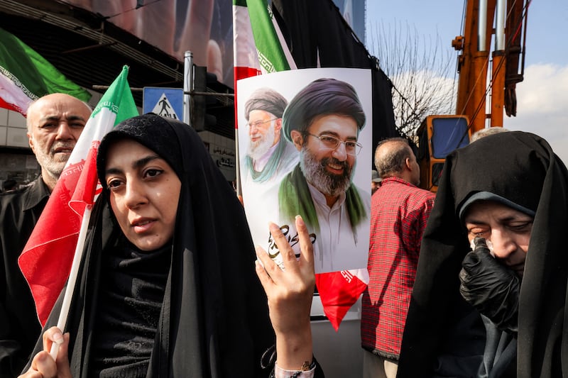 A woman holds a picture of Iran's new Supreme Leader Ayatollah Mojtaba Khamenei (R), next to his late father Ali Khamenei, during a rally in support of him at Enghelab Square in central Tehran on March 9, 2026. Iran marked the appointment of Ayatollah Mojtaba Khamenei to replace his father as its supreme leader with a new barrage of missiles against Israel and the Gulf states on Monday, as the Middle East war sent oil prices soaring. (Photo by ATTA KENARE / AFP via Getty Images)