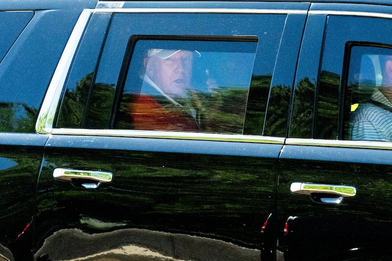 U.S. President Donald Trump talks on the phone as he departs the White House inb his limo