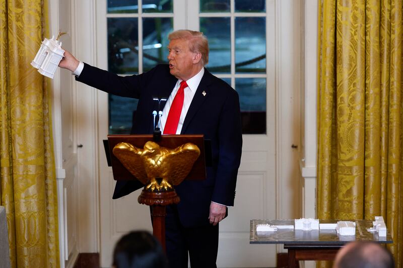 WASHINGTON, DC - OCTOBER 15: U.S. President Donald Trump holds models of an arch as he delivers remarks during a ballroom fundraising dinner in the East Room of the White House on October 15, 2025 in Washington, DC. Trump hosted organizations and individuals for a fundraising dinner for the new $250 million ballroom addition currently under construction at the White House. (Photo by Kevin Dietsch/Getty Images)