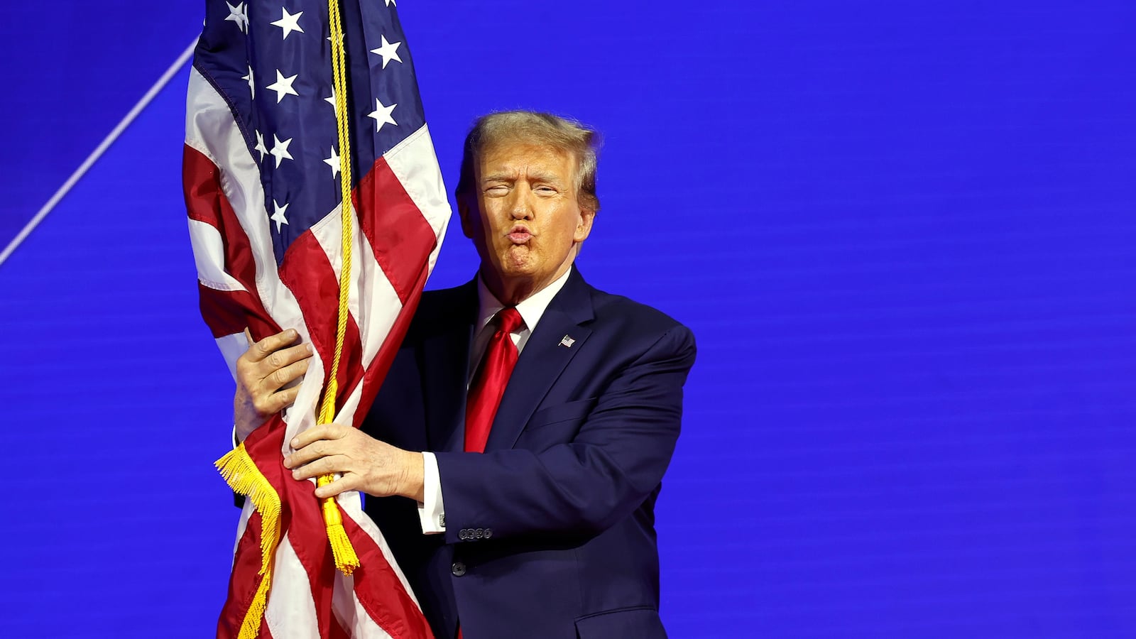 Donald Trump hugs an American flag as he arrives at the Conservative Political Action Conference (CPAC) at the Gaylord National Resort Hotel And Convention Center on February 24, 2024 in National Harbor, Maryland.