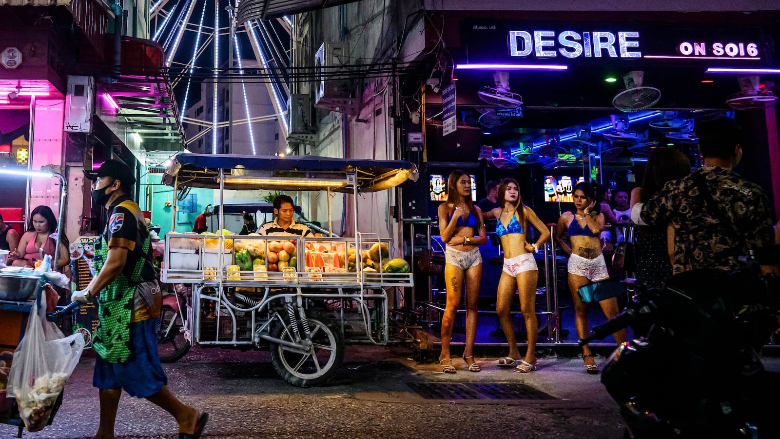 A street vendor pushes his cart past bars and clubs along a street in Pattaya on July 2, 2026. Scantily dressed and wearing stiletto heels, hundreds of girls, some apparently very young, form a seedy guard of honour under the lights of Soi 6, a street in one of Pattaya's red-light districts. (Photo by ANTHONY WALLACE / AFP via Getty Images) / TO GO WITH: Thailand-Australia-crime-tourism-prostitution