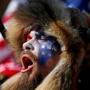 Jacob Chansley, wearing face paint and a fur hat, screams during a protest.