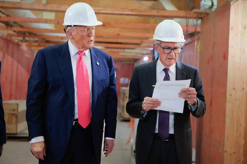 Federal Reserve Chair Jerome Powell looks at a piece of paper handed to him by President Donald Trump as they tour the Federal Reserve’s $2.5 billion headquarters renovation project on July 24, 2025 after Trump criticized the project cost going up to $3.1 billion. Powell pointed out that the president was including a third building in his claim that had previously been completed.
