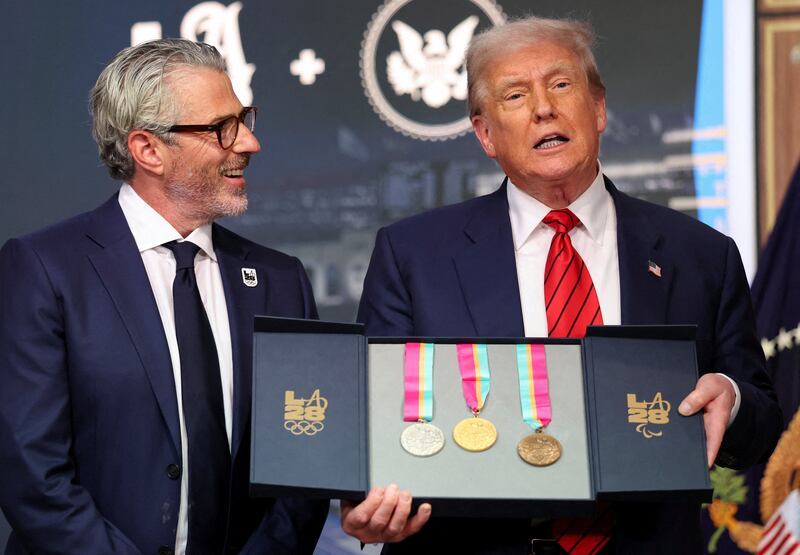 U.S. President Donald Trump, accompanied by LA28 Chairman Casey Wasserman, holds 1984 Los Angeles Olympics medals as he delivers remarks before signing an executive order to create a White House Olympics task force to handle security and other issues related to the LA 2028 Summer Olympics, in the South Court Auditorium on the White House campus in Washington, D.C., U.S., August 5, 2025. REUTERS/Jonathan Ernst